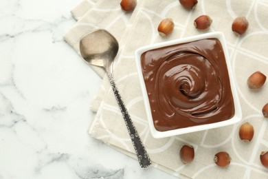 Photo of Tasty chocolate spread and hazelnuts on table, flat lay. Space for text