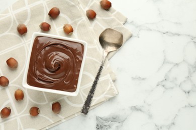 Photo of Tasty chocolate spread and hazelnuts on table, flat lay. Space for text