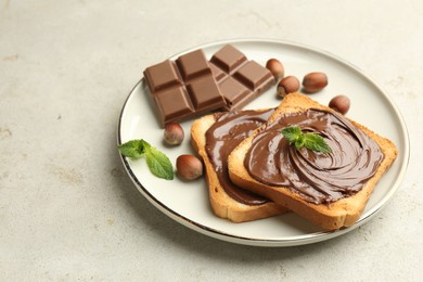 Photo of Toasts with tasty chocolate spread, pieces, mint and hazelnuts on light table, closeup