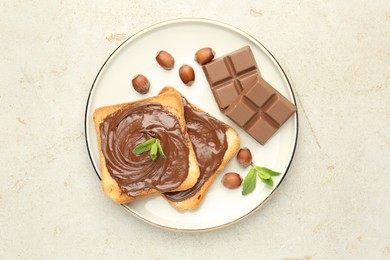 Photo of Toasts with tasty chocolate spread, pieces, mint and hazelnuts on light table, top view