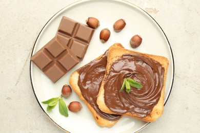 Photo of Toasts with tasty chocolate spread, pieces, mint and hazelnuts on light table, top view