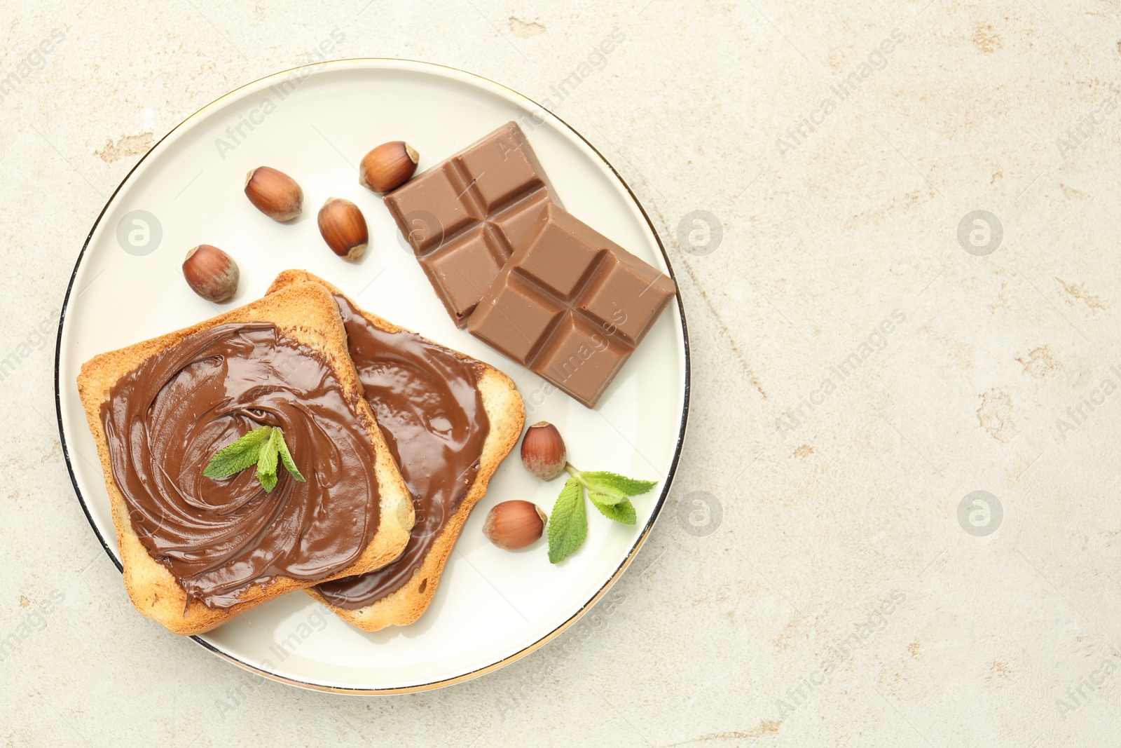 Toasts with tasty chocolate spread, pieces, mint and hazelnuts on light table, top view. Space for text Photo of Toasts with tasty chocolate spread, pieces, mint and hazelnuts on light table, top view. Space for text