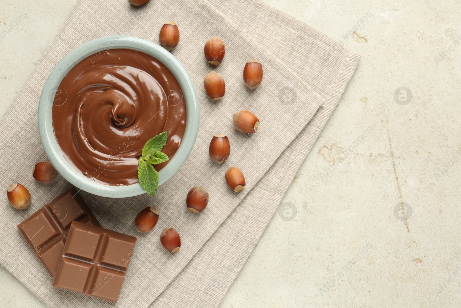 Tasty chocolate spread, pieces, mint and hazelnuts on light table, flat lay. Space for text Photo of Tasty chocolate spread, pieces, mint and hazelnuts on light table, flat lay. Space for text