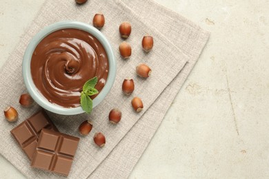 Photo of Tasty chocolate spread, pieces, mint and hazelnuts on light table, flat lay. Space for text