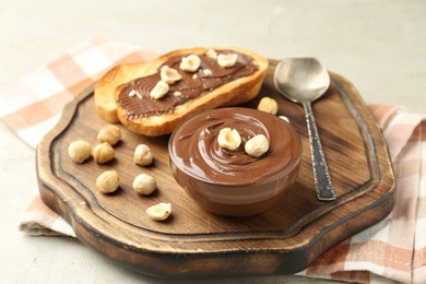 Photo of Toasts with tasty chocolate spread and hazelnuts on light table, closeup