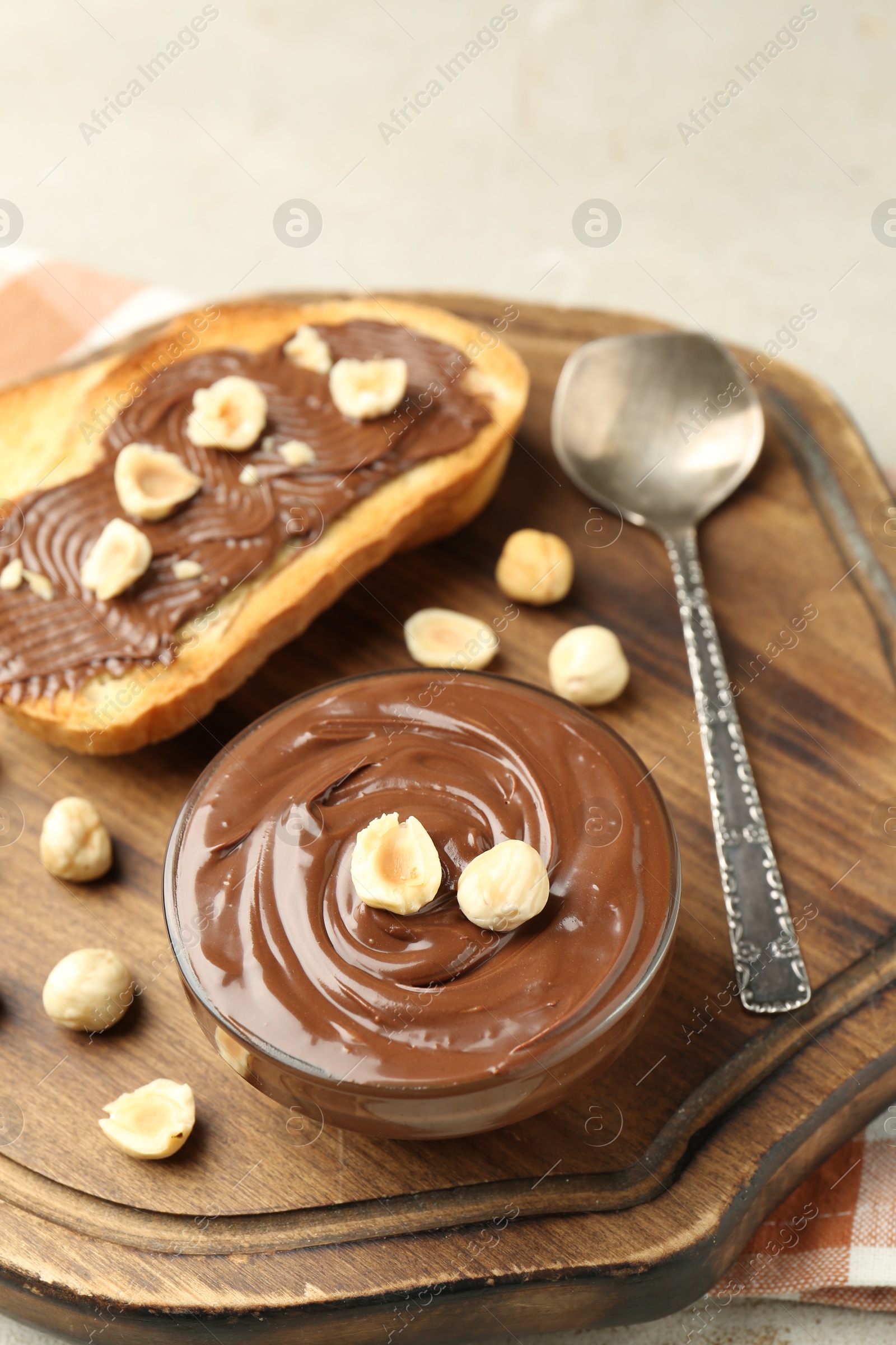 Toasts with tasty chocolate spread and hazelnuts on light table, closeup Photo of Toasts with tasty chocolate spread and hazelnuts on light table, closeup
