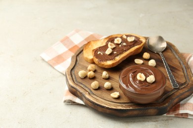 Photo of Toasts with tasty chocolate spread and hazelnuts on light table, closeup. Space for text