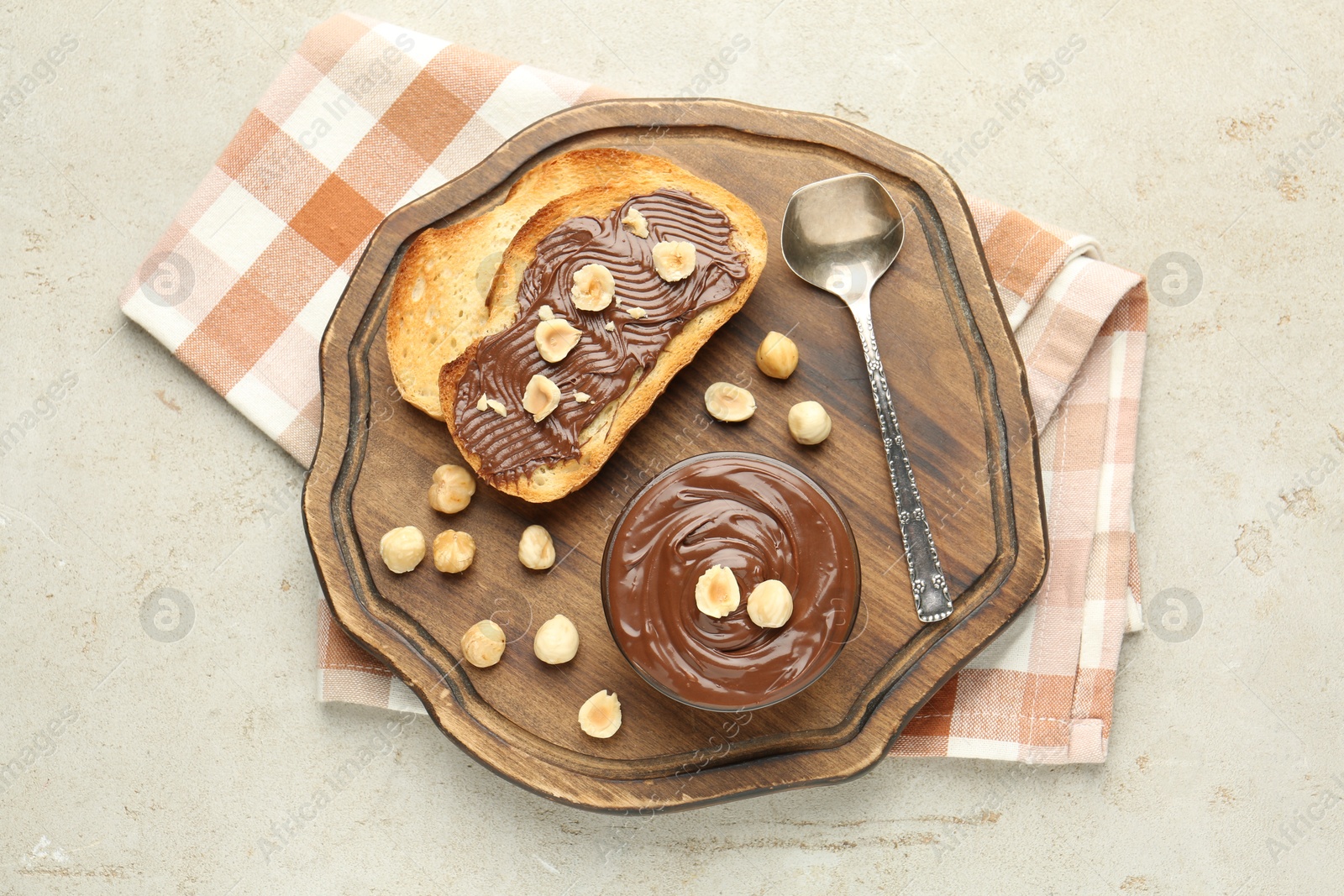 Photo of Toasts with tasty chocolate spread and hazelnuts on light table, top view