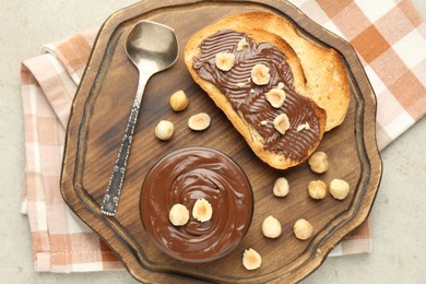 Photo of Toasts with tasty chocolate spread and hazelnuts on light table, top view