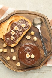 Photo of Toasts with tasty chocolate spread and hazelnuts on light table, top view
