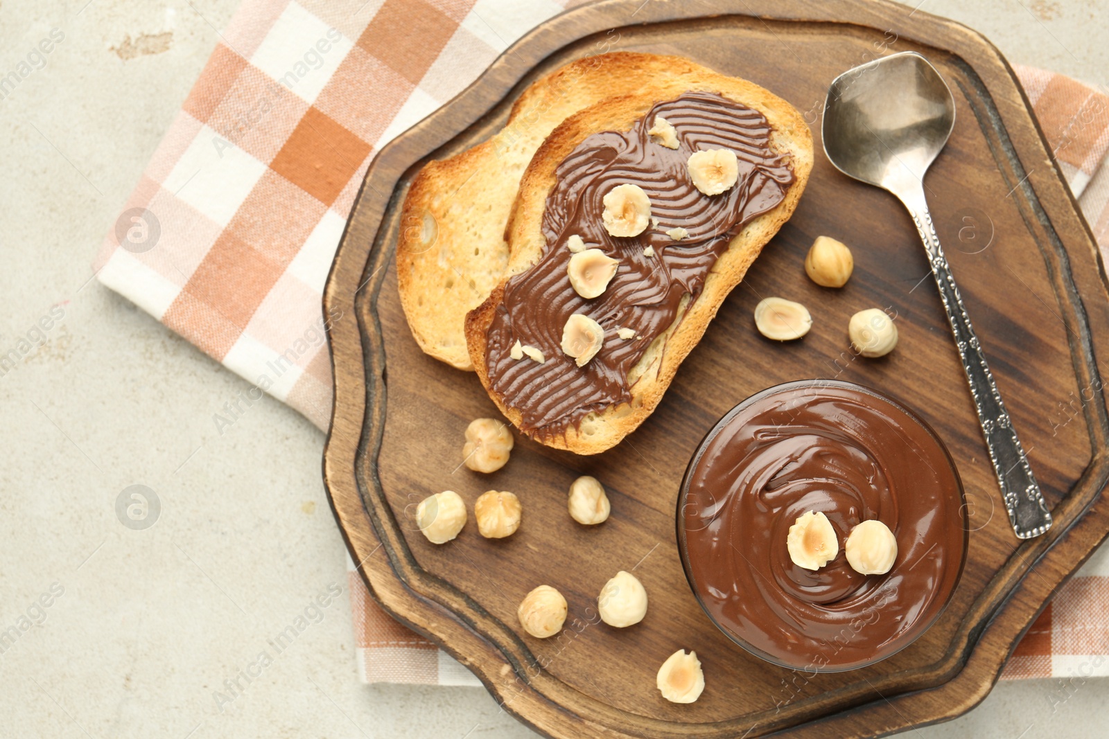 Photo of Toasts with tasty chocolate spread and hazelnuts on light table, top view