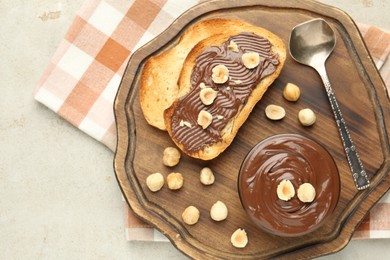 Photo of Toasts with tasty chocolate spread and hazelnuts on light table, top view
