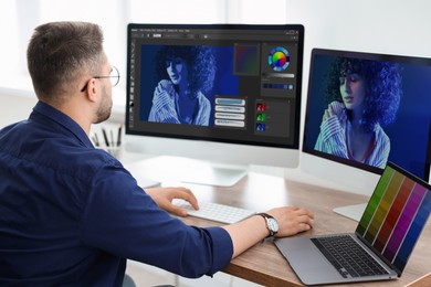 Image of Designer working on different computers at table in office