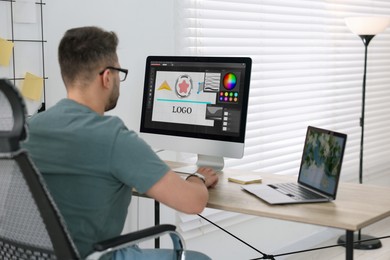 Image of Designer working on different computers at table in office