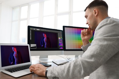 Image of Designer working on different computers at table in office