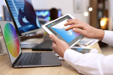 Image of Designer working on different devices at table in office. Man using tablet computer, closeup