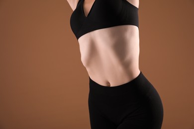 Photo of Attractive woman against brown background, closeup on belly. Space for text