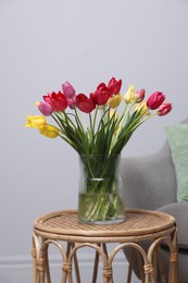 Photo of Bouquet of beautiful tulips on rattan table indoors