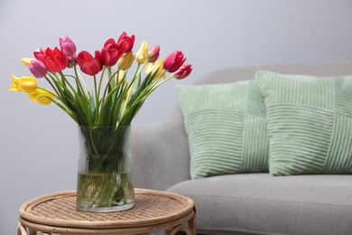 Photo of Bouquet of beautiful tulips on rattan table indoors. Space for text