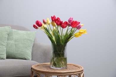 Photo of Bouquet of beautiful tulips on rattan table indoors