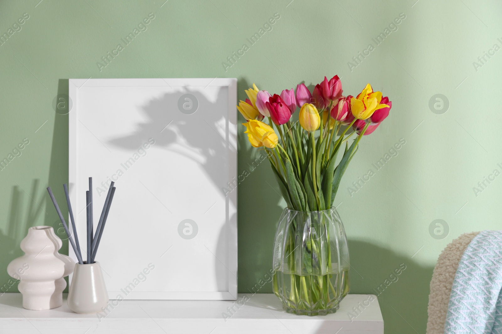Photo of Bouquet of beautiful tulips and decor on table near color wall