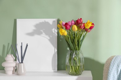 Photo of Bouquet of beautiful tulips and decor on table near color wall