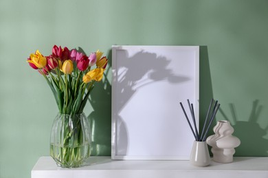 Photo of Bouquet of beautiful tulips and decor on table near color wall