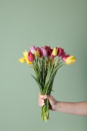 Photo of Woman with bouquet of beautiful tulips on green background, closeup