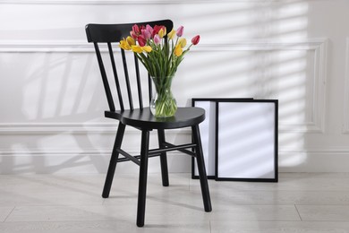 Photo of Bouquet of beautiful colorful tulips on chair indoors