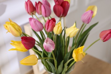 Photo of Bouquet of beautiful tulips on wooden table indoors, closeup