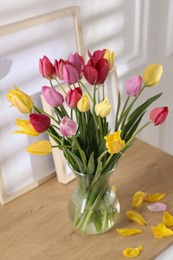 Photo of Bouquet of beautiful tulips and frames on wooden table indoors