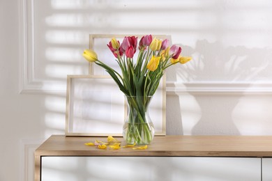Photo of Bouquet of beautiful tulips and frames on wooden table indoors