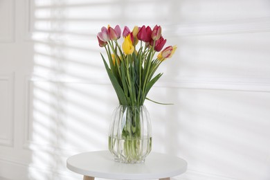 Photo of Bouquet of beautiful tulips on table near white wall