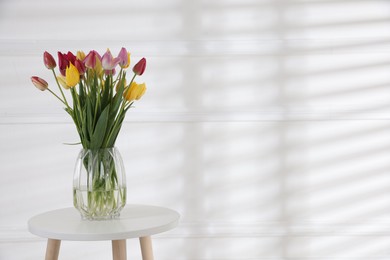 Photo of Bouquet of beautiful tulips on table near white wall. Space for text