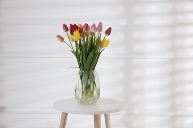 Photo of Bouquet of beautiful tulips on table near white wall