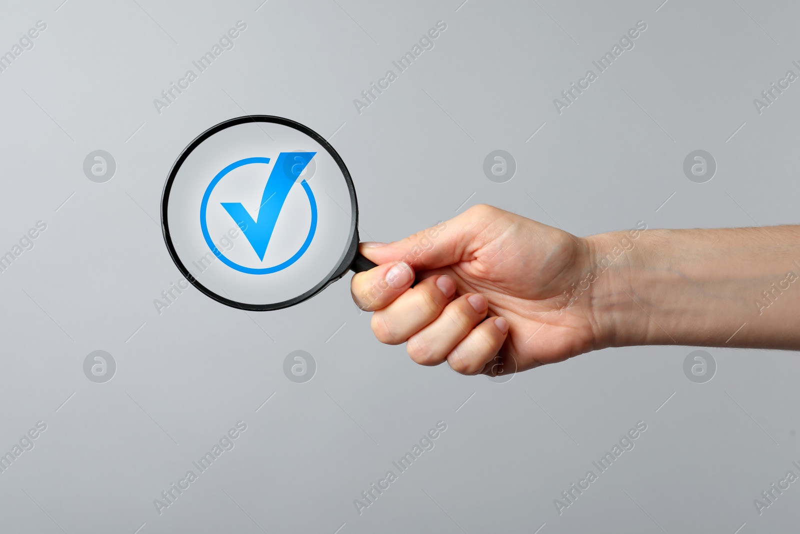Approved. Woman holding magnifying glass with check mark inside on grey background, closeup Image of Approved. Woman holding magnifying glass with check mark inside on grey background, closeup