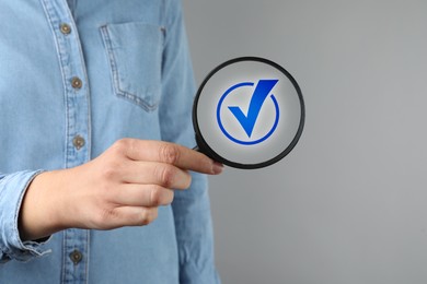 Image of Approved. Woman holding magnifying glass with check mark inside on grey background, closeup