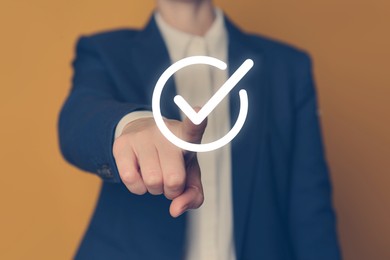 Image of Approved. Woman touching check mark on virtual screen against orange background, closeup