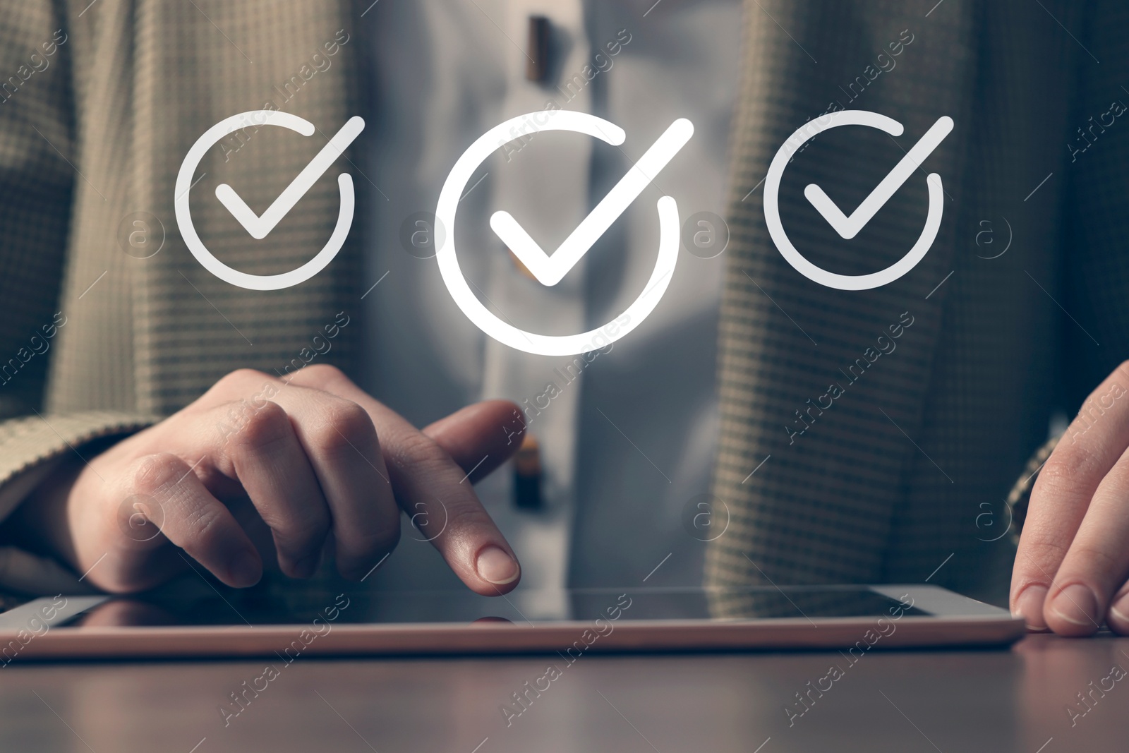 Approved. Woman using tablet at table, closeup. Check marks above device Image of Approved. Woman using tablet at table, closeup. Check marks above device