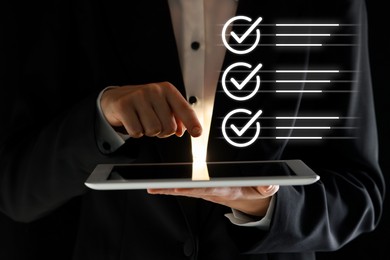 Image of Approved. Man using tablet on black background, closeup. Check marks above device