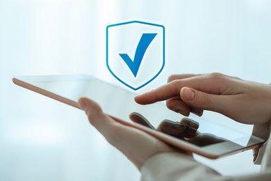 Image of Approved. Woman using tablet indoors, closeup. Check mark above device