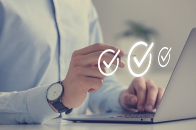 Image of Approved. Man using laptop and touching virtual screen with check marks at table, closeup