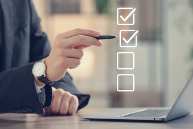Image of Approved. Man using laptop and checking boxes on virtual screen at table, closeup