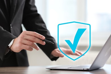 Image of Approved. Man using laptop at table, closeup. Check mark above device