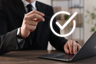 Image of Approved. Man using laptop and touching virtual screen with check mark at table, closeup