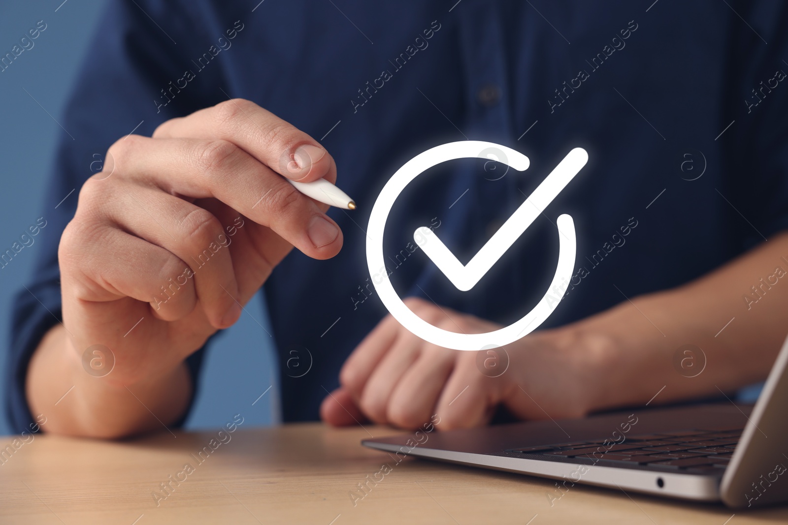 Approved. Man using laptop and touching virtual screen with check mark at table, closeup Image of Approved. Man using laptop and touching virtual screen with check mark at table, closeup