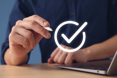 Image of Approved. Man using laptop and touching virtual screen with check mark at table, closeup