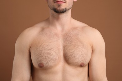 Photo of Young man with hairy chest on brown background, closeup. Epilation procedure