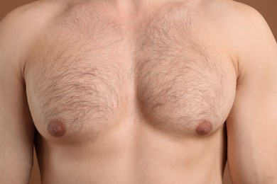 Photo of Young man with hairy chest on brown background, closeup. Epilation procedure