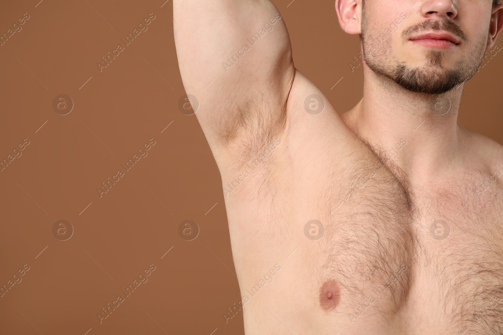 Young man showing hairy armpit on brown background, closeup. Epilation procedure Photo of Young man showing hairy armpit on brown background, closeup. Epilation procedure